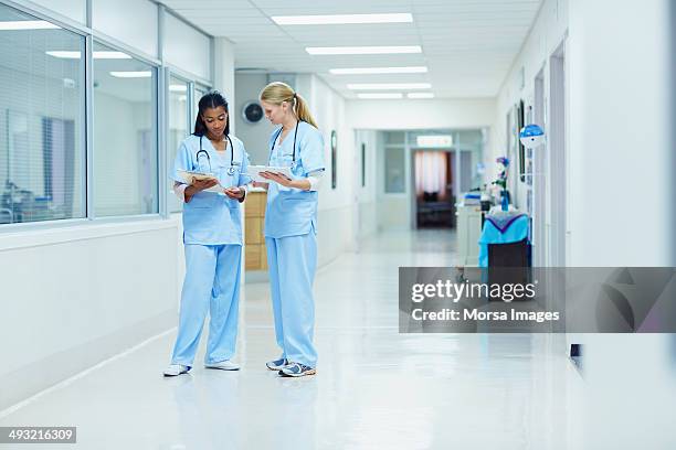 nurses discussing medical documents in hospital - corridor stock-fotos und bilder