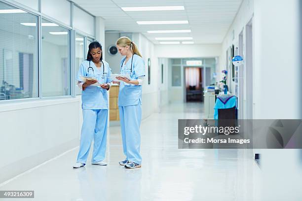 nurses discussing medical documents in hospital - corridor foto e immagini stock