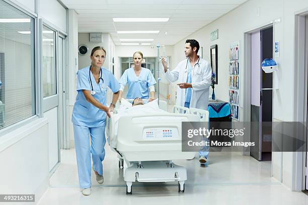 healthcare workers rushing patient in hospital - stretcher stock-fotos und bilder
