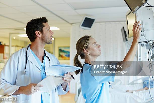 doctors operating monitoring equipment in icu - critical care stock pictures, royalty-free photos & images