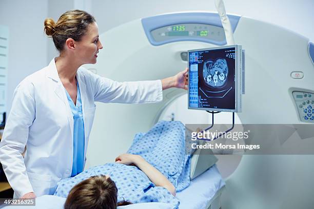 doctor showing ct scan to patient - instrumentos fotografías e imágenes de stock