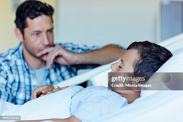 tensed father with ill son sleeping in hospital - child hospital bed stockfoto's en -beelden