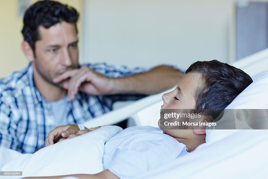 Tensed father with ill son sleeping in hospital