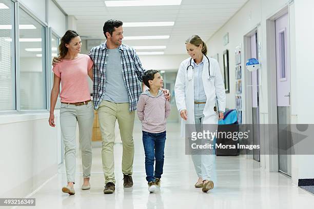 doctor walking with family in hospital corridor - doctors walking stock-fotos und bilder