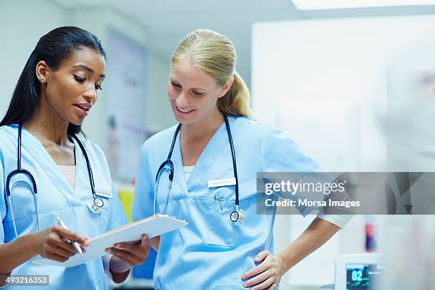 nurses discussing over documents in hospital - communication nurse stock pictures, royalty-free photos & images