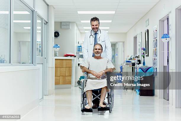 doctor pushing disabled man in wheelchair - doctor stethoscope patient whole body stock pictures, royalty-free photos & images