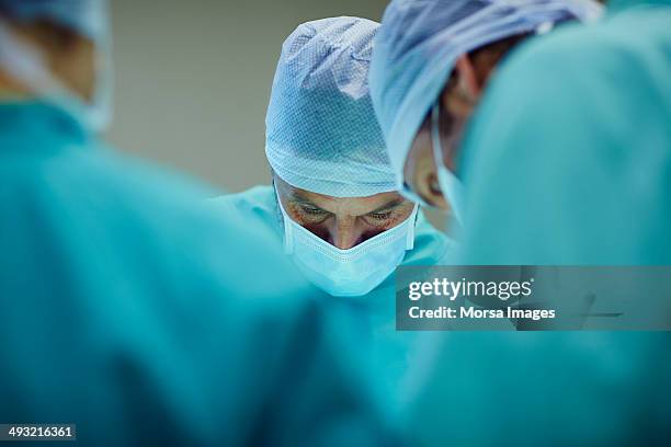 surgeons working in operating room - opération chirurgicale photos et images de collection