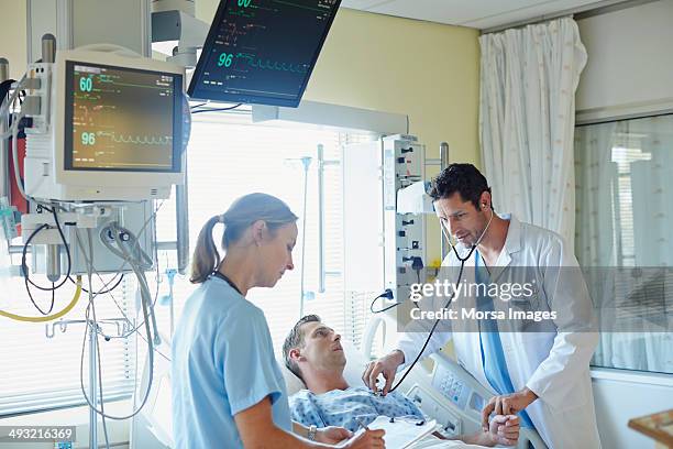 doctor examining man with colleague - intensieve zorg stockfoto's en -beelden