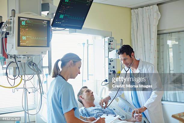 doctor examining man with colleague - critical care bildbanksfoton och bilder