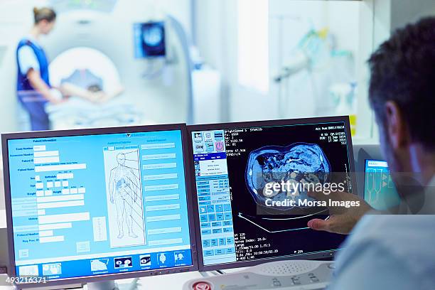 doctor running ct scan from control room - patient room stockfoto's en -beelden