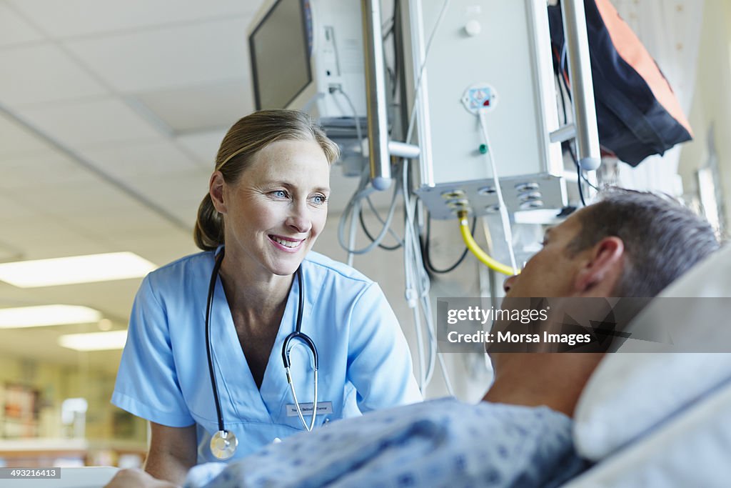 Smiling doctor looking at patient in hospital ward