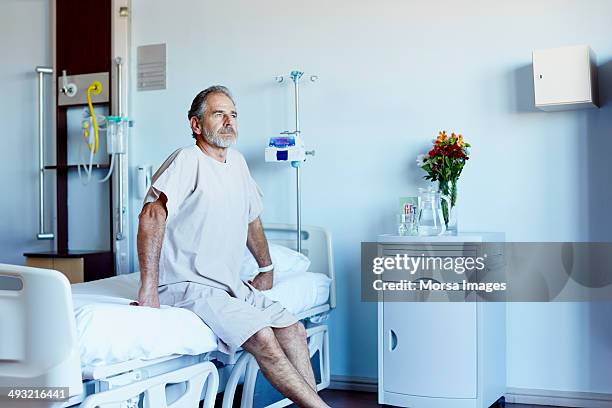 thoughtful mature man in hospital ward - man sitting up in hospital bed stock pictures, royalty-free photos & images