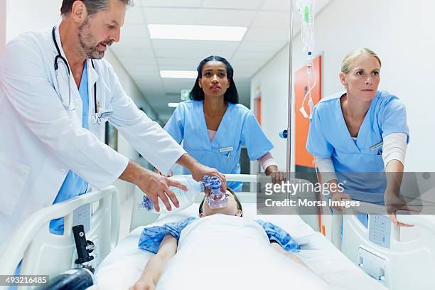 doctor and nurses rushing patient in corridor - unfall und katastrophe stock-fotos und bilder