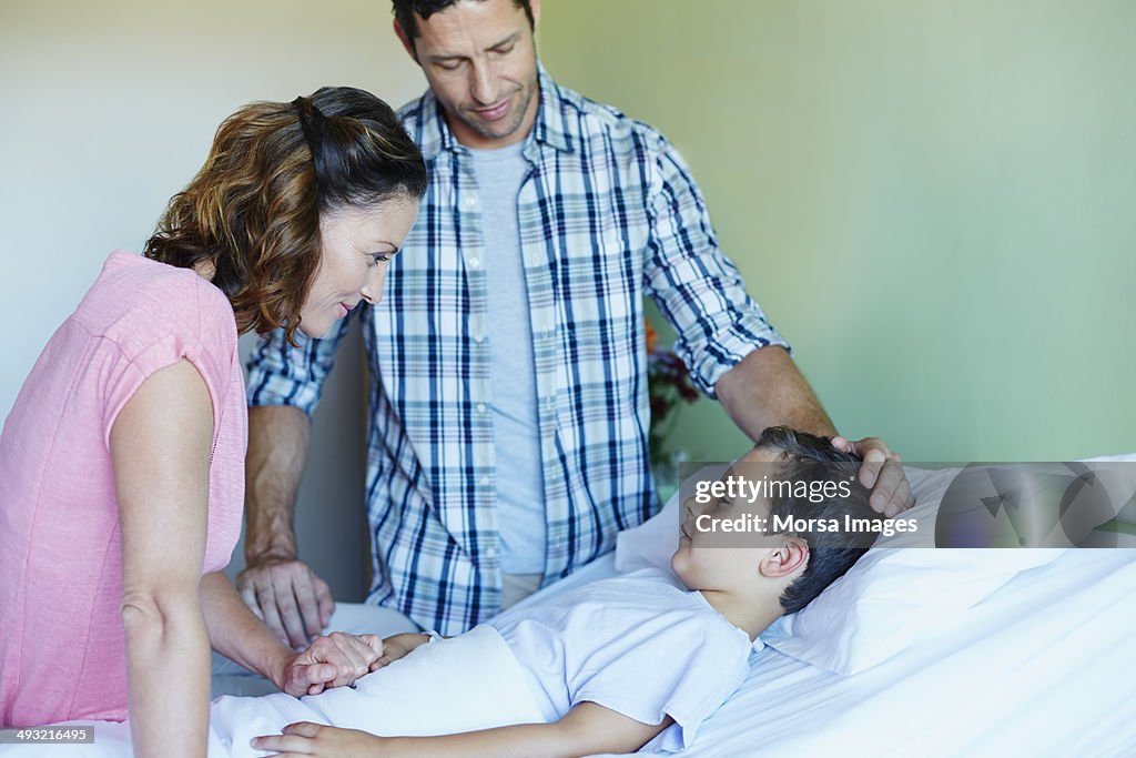 Parents with ill son lying in hospital bed