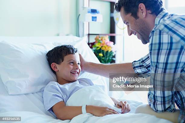 loving father with ill son in hospital ward - children hospital stock pictures, royalty-free photos & images