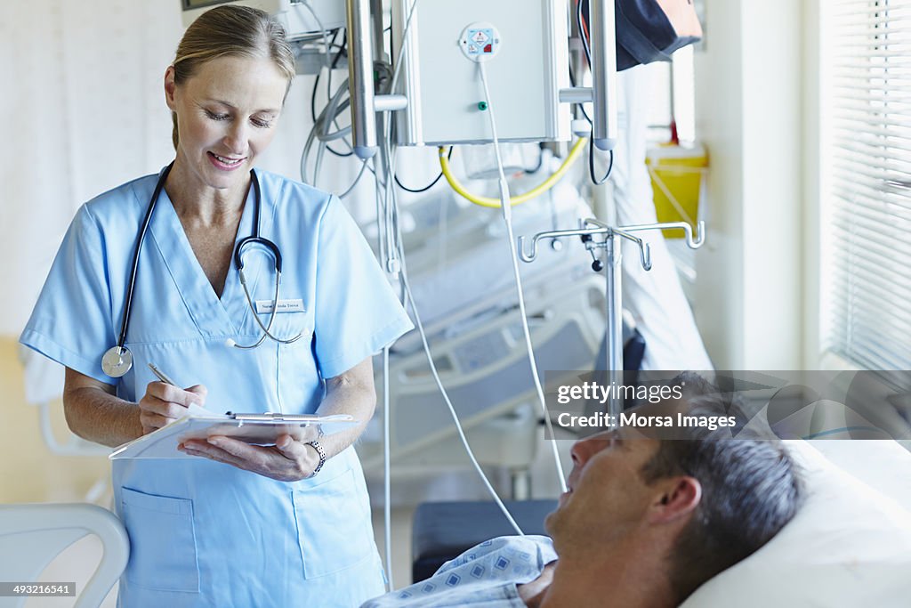 Doctor writing notes while talking to patient