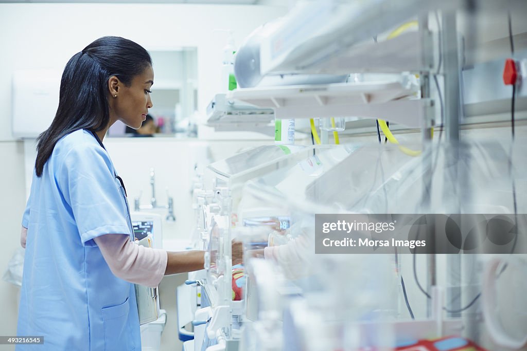 Nurse taking care of baby in incubator