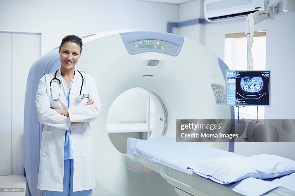 Confident female doctor standing by CT scanner