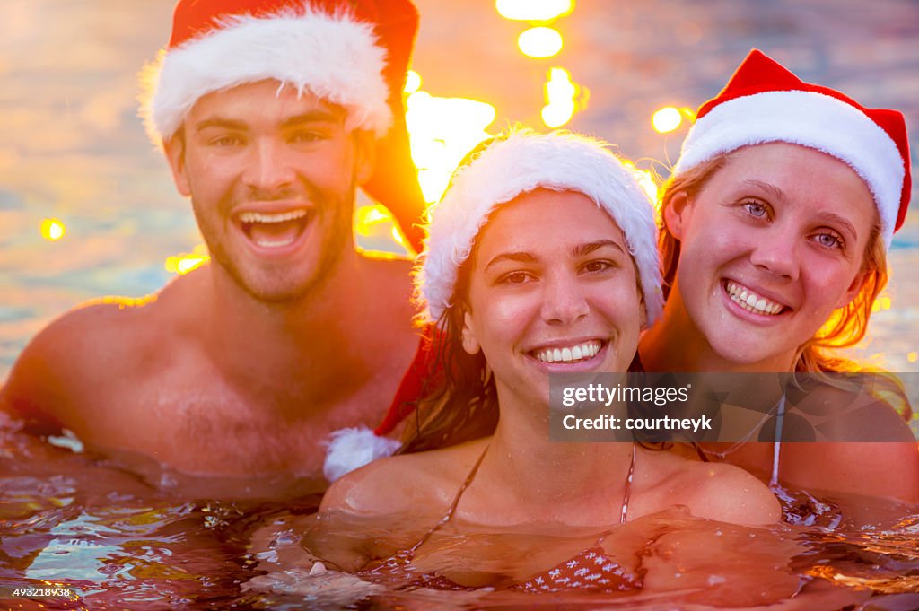 Group of friends swimming with Santa hats.