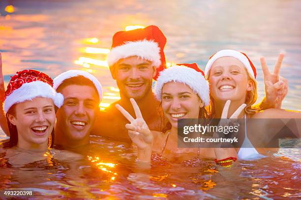 group of friends swimming with santa hats. - santa swimming stockfoto's en -beelden