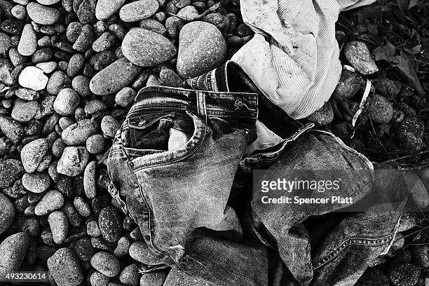 Pair of childs jeans lays next to other items discarded by migrants arriving by boat from Turkey along a Lesbos beach where thousands of objects can...