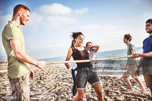 freunde spielen limbo am strand - limbo stock-fotos und bilder