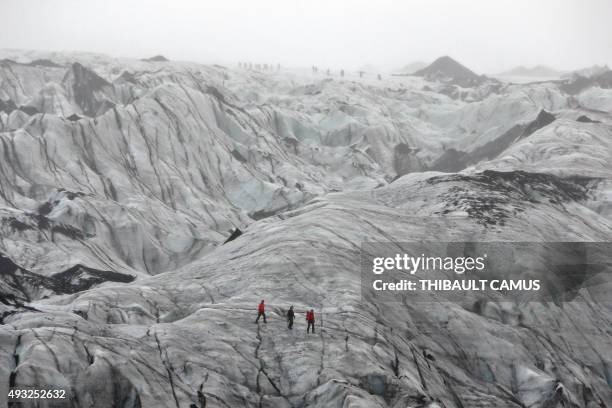 Photo taken on October 16, 2015 shows tourists walking on the Solheimajokull glacier where the ice has retreated by more than 1 kilometer since...