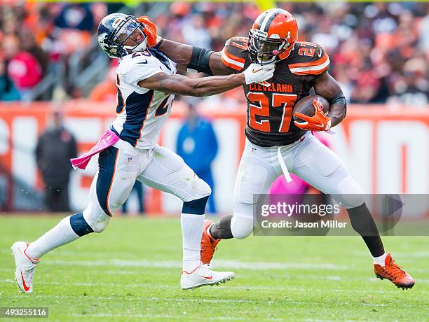 Cornerback Chris Harris of the Denver Broncos puts pressure on running back Robert Turbin of the Cleveland Browns during the first half at...