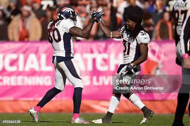 David Bruton of the Denver Broncos is high-fived by Omar Bolden after making an interception on a pass by Josh McCown of the Cleveland Browns with 44...