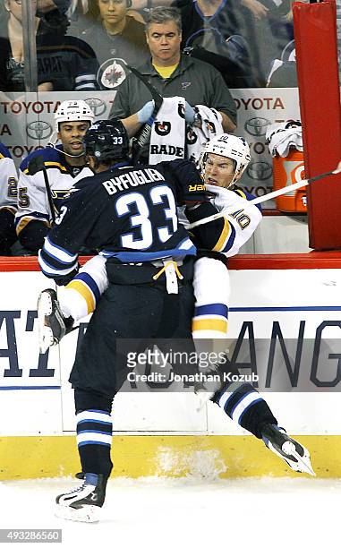 Dustin Byfuglien of the Winnipeg Jets checks Scottie Upshall of the St. Louis Blues into the bench during third period action at the MTS Centre on...