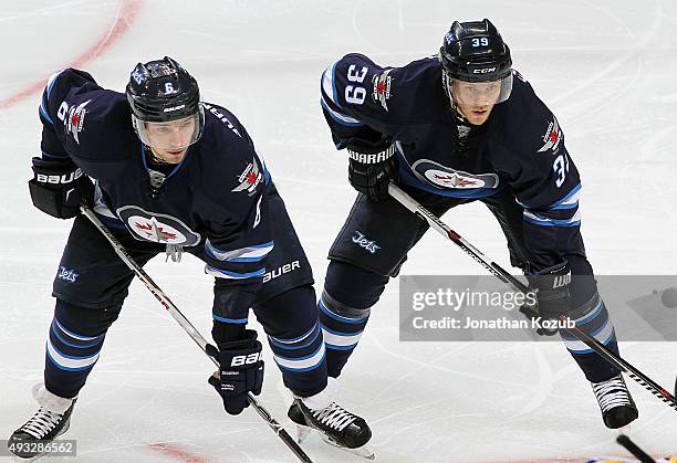 Alexander Burmistrov and Toby Enstrom of the Winnipeg Jets get set for a third period face-off against the St. Louis Blues at the MTS Centre on...