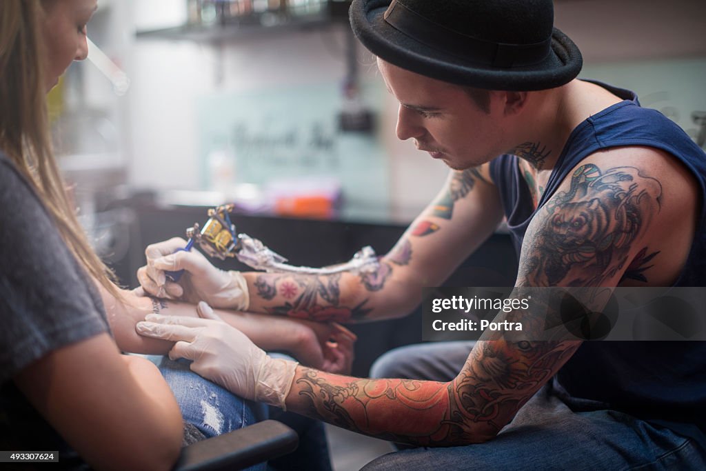 Artiste faisant de tatouage sur le client de la main dans le studio