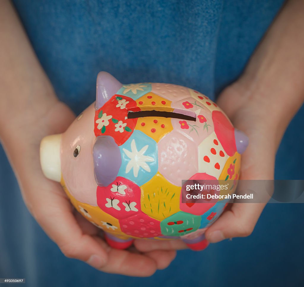 Hands holding colourful piggy bank