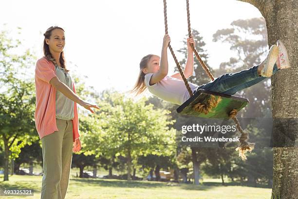mother pushing girl on swing - using a swing stock pictures, royalty-free photos & images