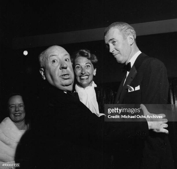 Director Alfred Hitchcock talk to actor Jimmy Stewart and his wife Gloria Hatrick McLean as they attend the premier of "The Man Who Knew Too Much" in...