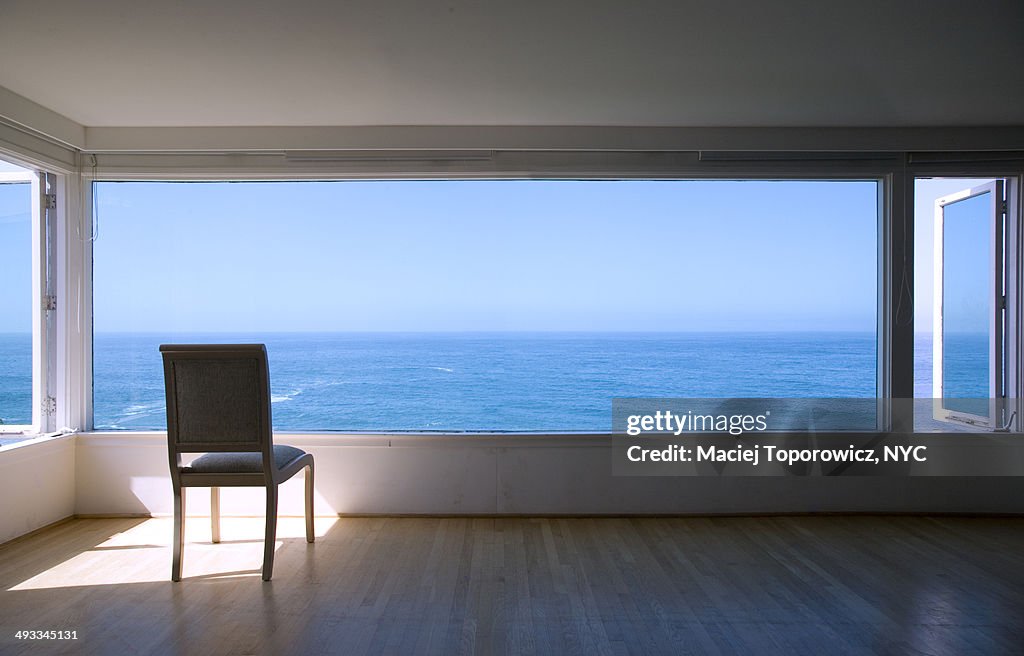 Room with a view of ocean and empty chair.