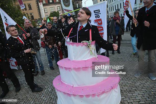 Satirical counter-demonstrators, including one dressed as Adolf Hitler and wearing a cake, pretend to celebrate the first anniversary since the first...