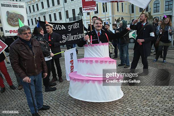 Satirical counter-demonstrators, including one dressed as Adolf Hitler and wearing a cake, pretend to celebrate the first anniversary since the first...