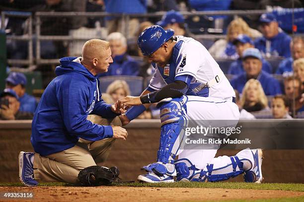 Trainer checks on Kansas City Royals' catcher Salvador Perez after he was hit on the hand by the bat of Toronto Blue Jays' Josh Donaldson during...