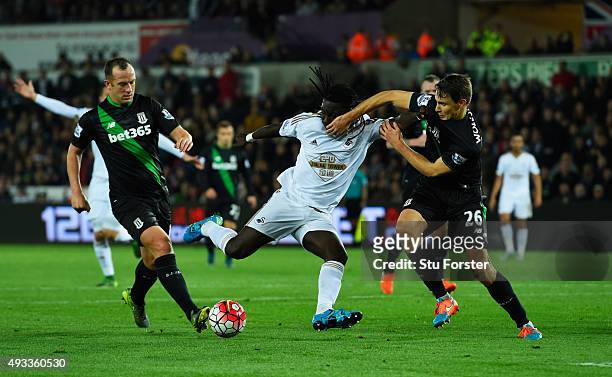 Bafetimbi Gomis of Swansea City is blocked by Philipp Wollscheid and Charlie Adam of Stoke City during the Barclays Premier League match between...