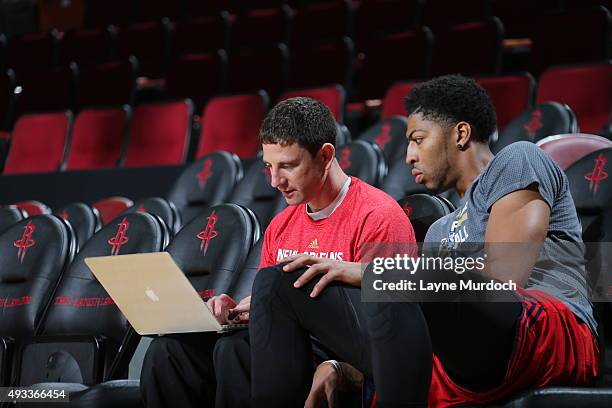 Anthony Davis of the New Orleans Pelicans looks at a laptop with associate assistant coach Darren Erman before the game against the Houston Rockets...