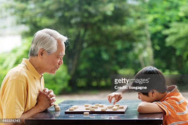 großvater und enkel spielt schach xiangqi (chinesisch) - 2014 asian games stock-fotos und bilder