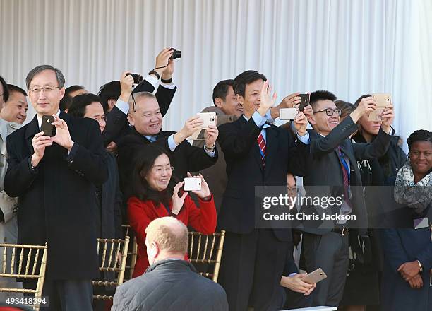 Members of the Chinese delegation take photographs on smart phones as Queen Elizabeth II and Chinese President Xi Jinping board the carriage during...