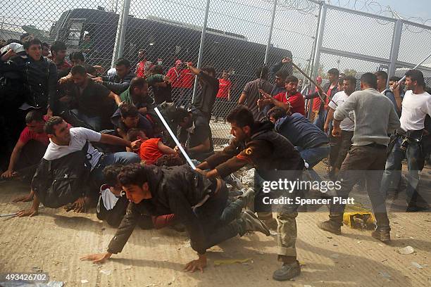 People flee from Afghan men with sticks as they fight with other recently arrived migrants waiting to be processed at the increasingly overwhelmed...