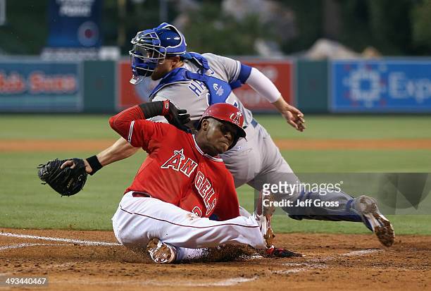 Erick Aybar of the Los Angeles Angels of Anaheim slides safely past the tag of catcher Brett Hayes of the Kansas City Royals and scores a run in the...