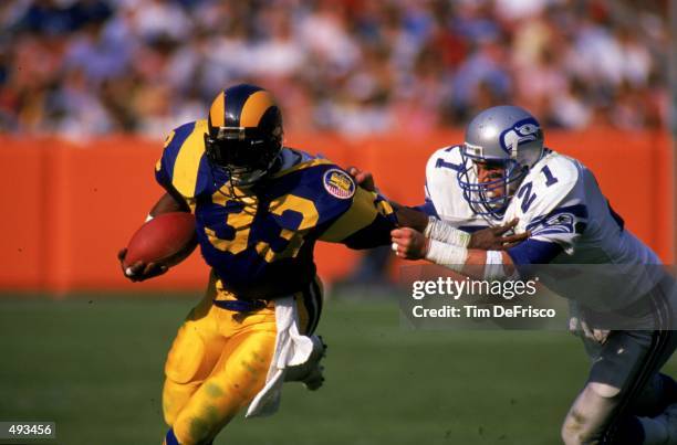 Charles White of the Los Angeles Rams runs with the ball as Paul Moyer of the Seattle Seahawks tries to pull him down during the game. The Rams...