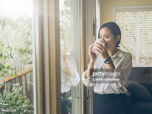 standing asian woman looking out   window at home - seattle coffee stock pictures, royalty-free photos & images