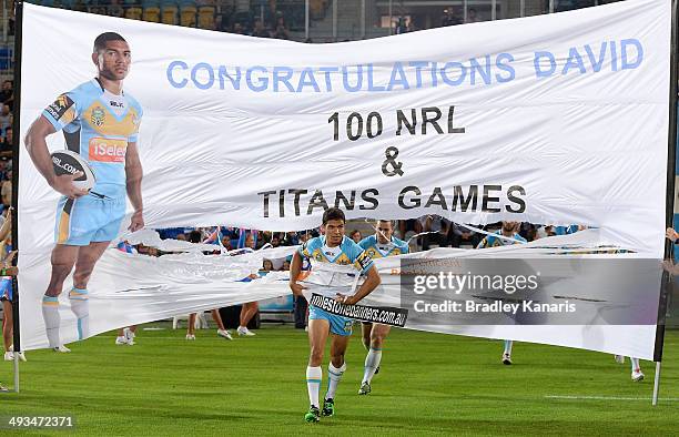 David Mead of the Titans runs through a banner to celebrate his 100th first grade match before the round 11 NRL match between the Gold Coast Titans...