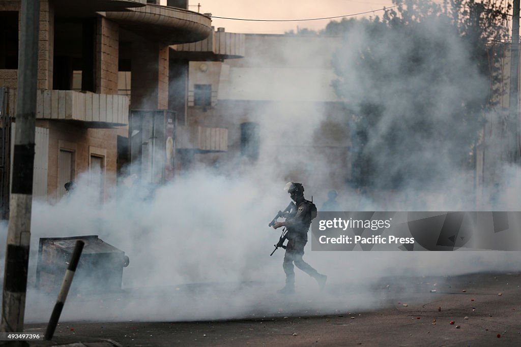 An Israeli soldier walks through tear gas during clashes...