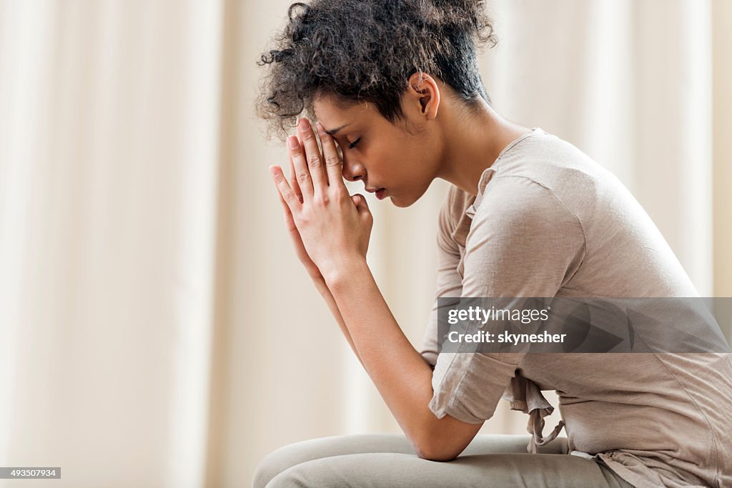 African American woman praying at home.